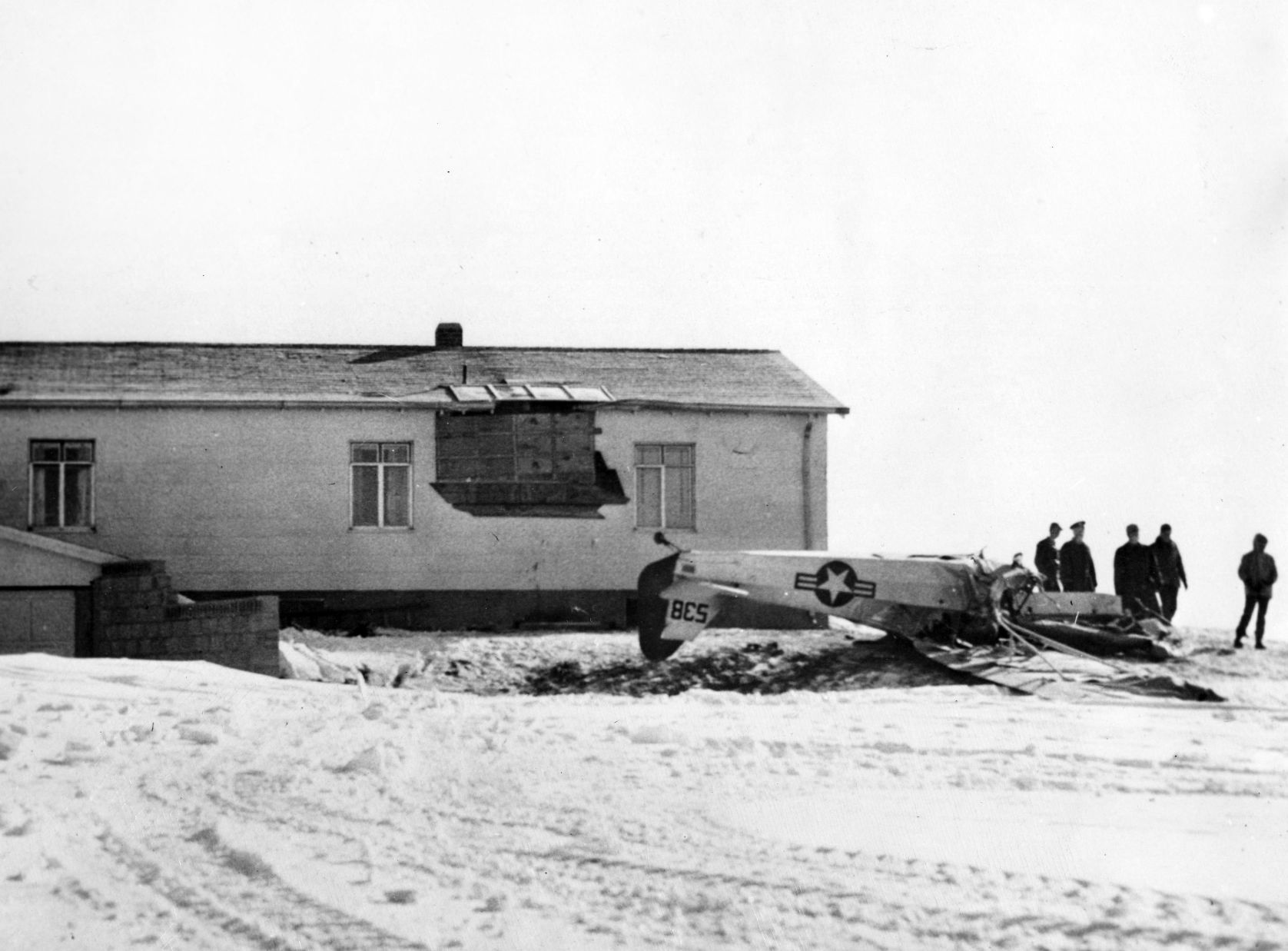 War Department inspectors look over the wreckage of a Civil Air Patrol plane which struck a high tension wire and ran into a house in Alliance while returning from a flight to deliver emergency rations and mail to snowbound ranchers. Pilot Clarence Kirkpatrick and observer John Huff died in the crash. February 9, 1949.